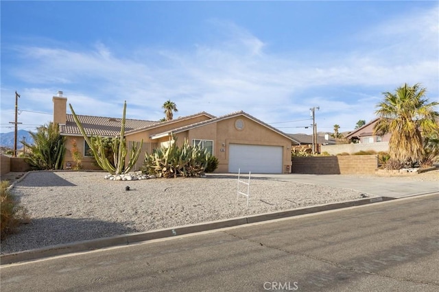 9551 San Rafael Dr, Desert Hot Springs, CA 92240 - ranch-style home featuring concrete driveway, stucco siding, an attached garage, a tile roof, and a chimney