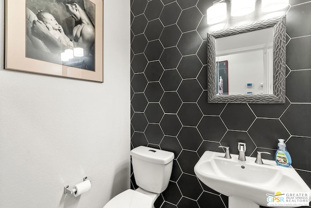 bathroom with backsplash, sink, tile walls, and toilet