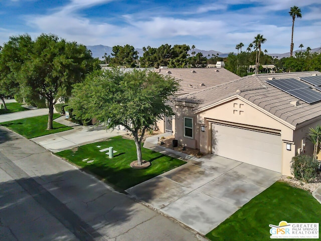 single story home with a mountain view, a front lawn, and a garage