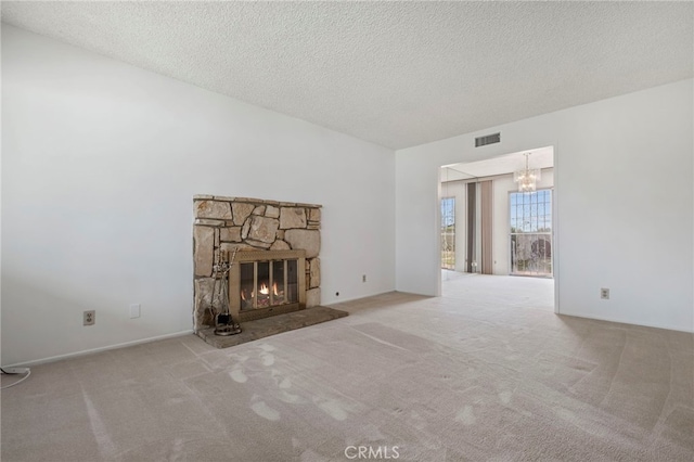 unfurnished living room featuring light carpet, a textured ceiling, and a stone fireplace