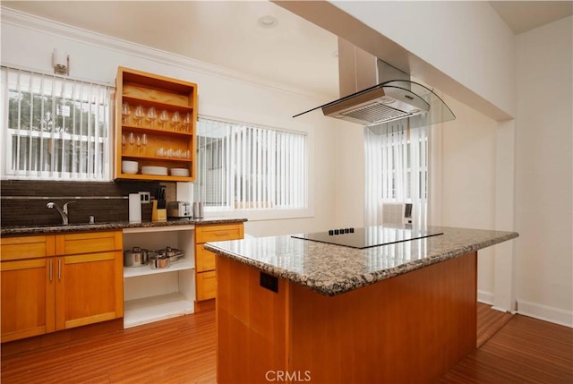 kitchen with light hardwood / wood-style flooring, backsplash, dark stone counters, black electric cooktop, and a kitchen island