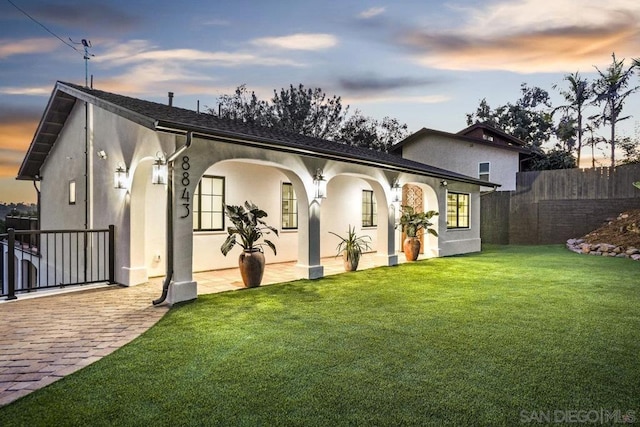 back house at dusk featuring a yard