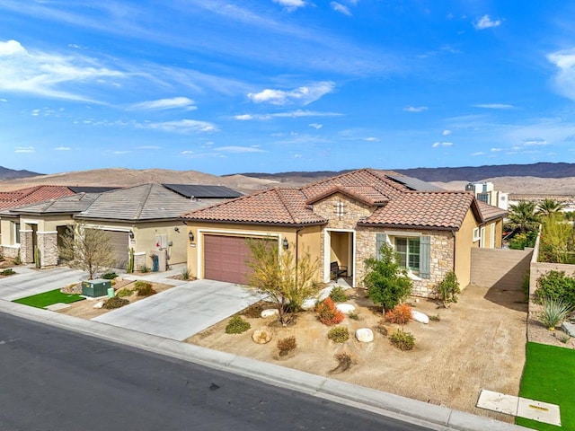 view of front facade with a garage, a mountain view, and solar panels