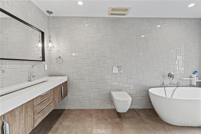 bathroom with vanity, a tub to relax in, toilet, and tile walls