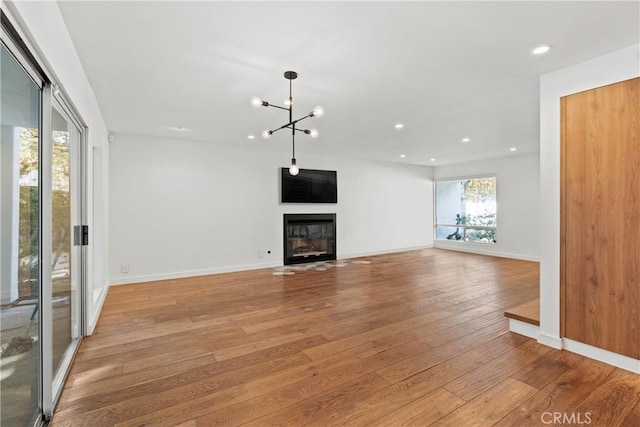 unfurnished living room with light hardwood / wood-style flooring and a chandelier