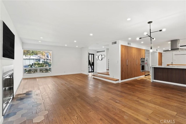 unfurnished living room with a chandelier and light wood-type flooring