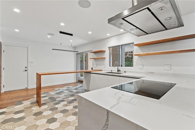 kitchen with black electric stovetop, light stone counters, exhaust hood, sink, and white cabinetry