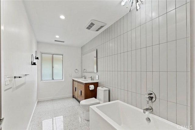 bathroom with vanity, tile walls, and toilet