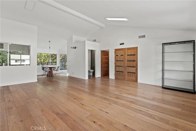 unfurnished living room featuring beamed ceiling, high vaulted ceiling, and light wood-type flooring