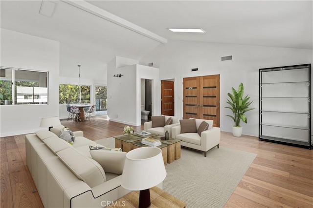 living room with beam ceiling, high vaulted ceiling, and light hardwood / wood-style flooring