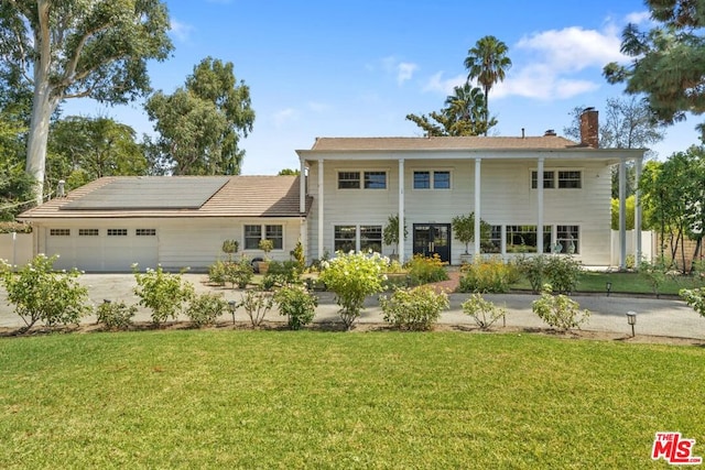 view of front of house featuring solar panels, a garage, and a front lawn