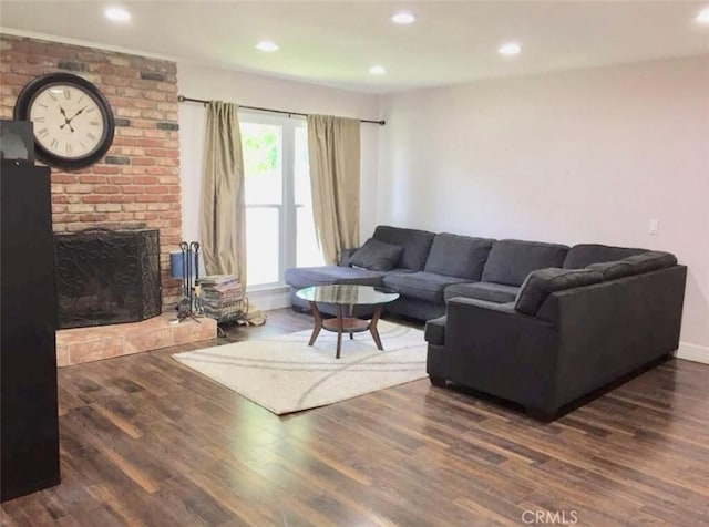 living room featuring dark hardwood / wood-style flooring and a brick fireplace