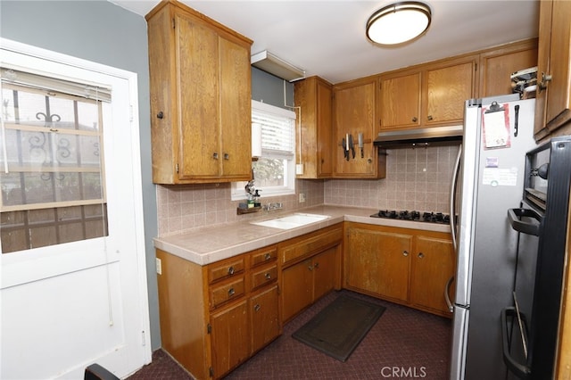 kitchen featuring gas cooktop, stainless steel refrigerator, tasteful backsplash, and sink