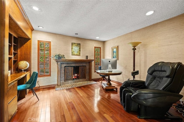 sitting room with a fireplace, built in study area, a textured ceiling, and hardwood / wood-style floors