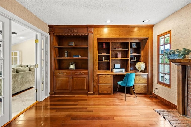 office space featuring a textured ceiling, light wood-style flooring, and built in study area