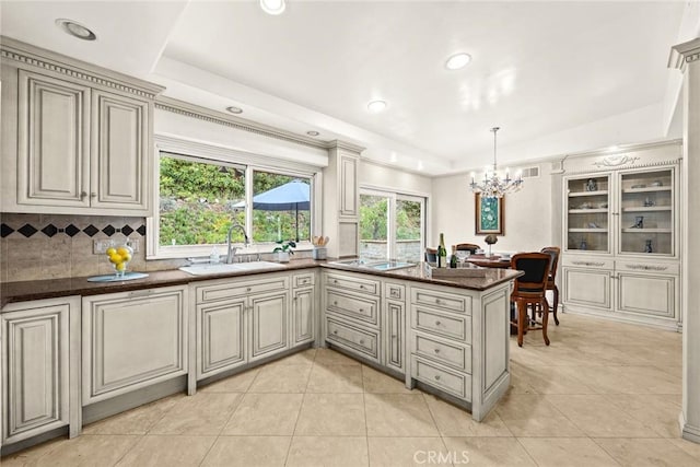 kitchen with a sink, a tray ceiling, a peninsula, white electric stovetop, and decorative backsplash