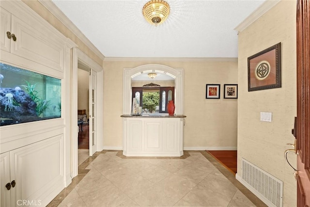 hallway with visible vents, a textured ceiling, crown molding, and baseboards