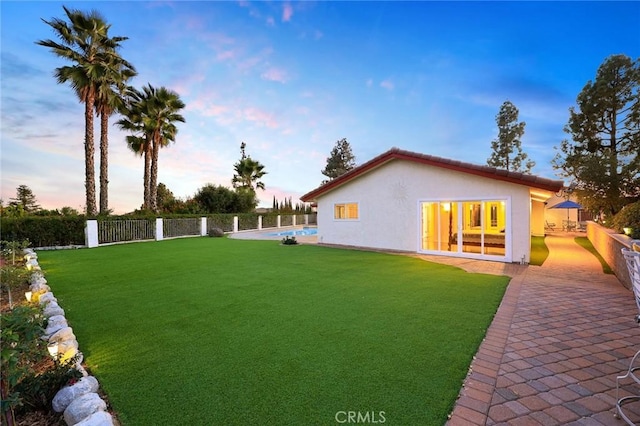 yard at dusk with a patio, fence, and a fenced in pool