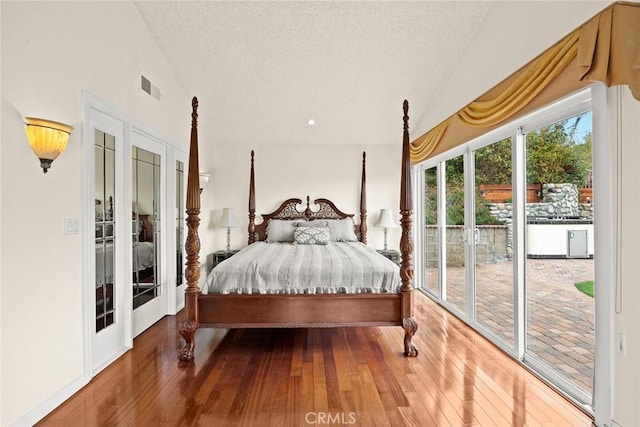 bedroom with access to exterior, lofted ceiling, and hardwood / wood-style flooring