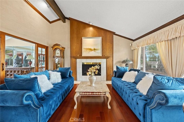 living area with a tiled fireplace, ornamental molding, lofted ceiling with beams, and wood finished floors