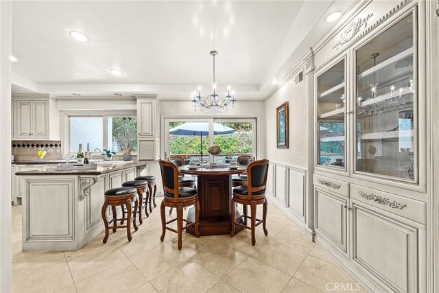 dining space with a chandelier, wainscoting, recessed lighting, a decorative wall, and a raised ceiling