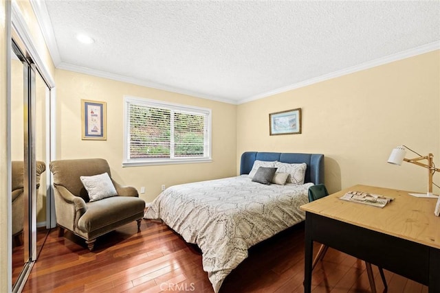 bedroom featuring a closet, wood-type flooring, a textured ceiling, and crown molding