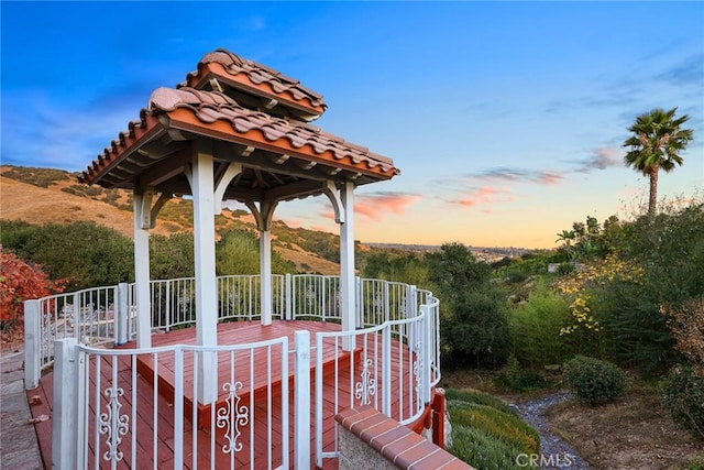 deck at dusk featuring a gazebo