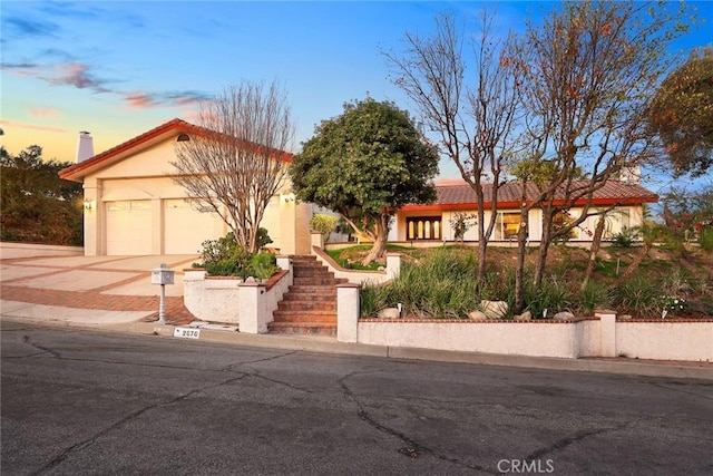 view of front of home featuring a tile roof, stucco siding, driveway, and an attached garage