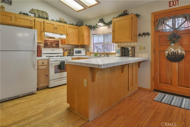 kitchen featuring light wood-type flooring, white appliances, tile countertops, and kitchen peninsula