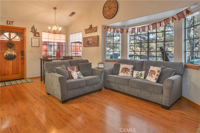 living room featuring hardwood / wood-style flooring, a healthy amount of sunlight, lofted ceiling, and an inviting chandelier