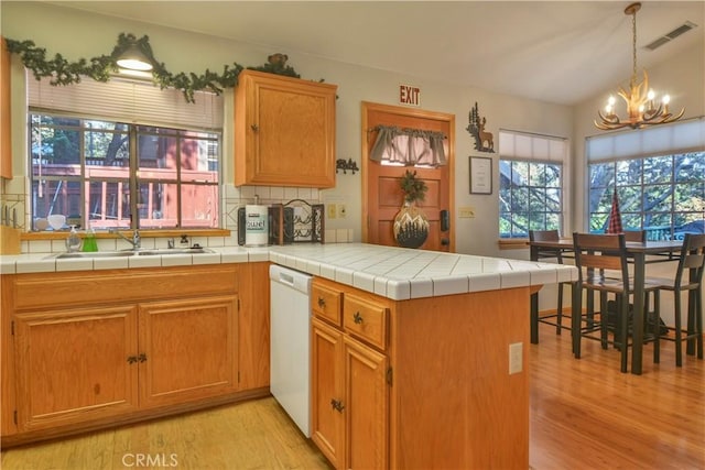 kitchen with tile countertops, white dishwasher, light hardwood / wood-style flooring, a notable chandelier, and kitchen peninsula