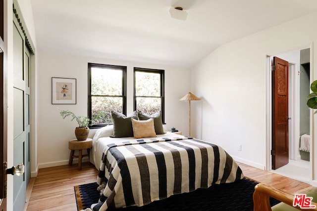 bedroom with vaulted ceiling and light wood-type flooring