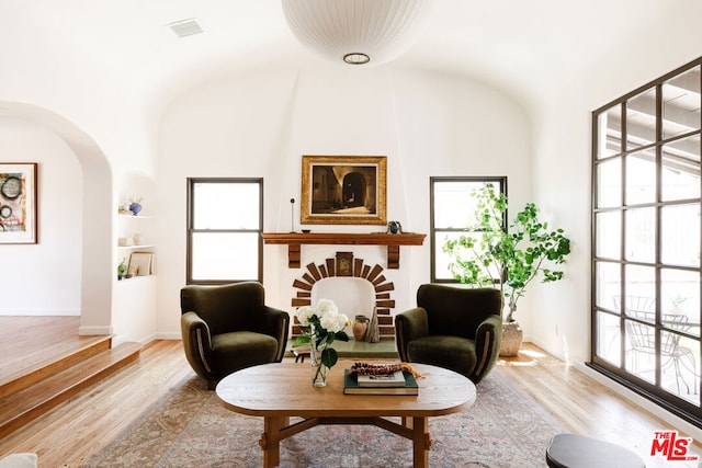 living area with light hardwood / wood-style flooring, high vaulted ceiling, and plenty of natural light