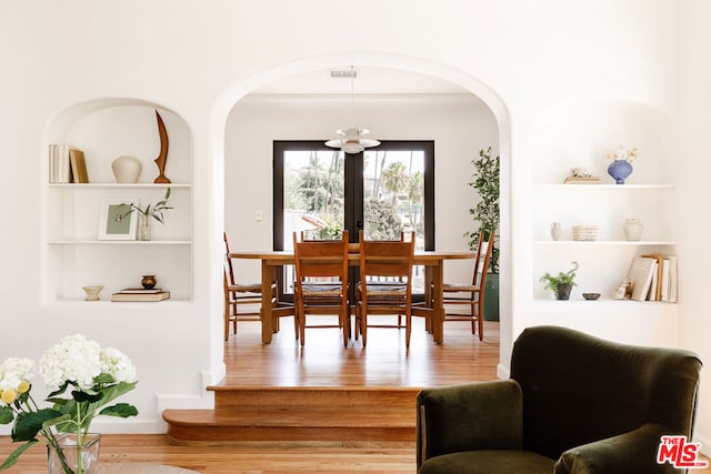 dining area with wood-type flooring, french doors, and built in shelves