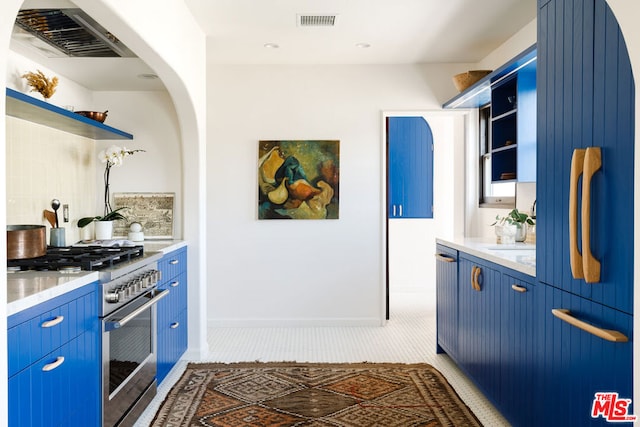 kitchen featuring blue cabinetry, dark tile patterned flooring, high end stainless steel range oven, and fridge