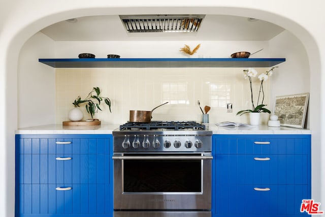 kitchen featuring blue cabinetry, stainless steel range, and range hood