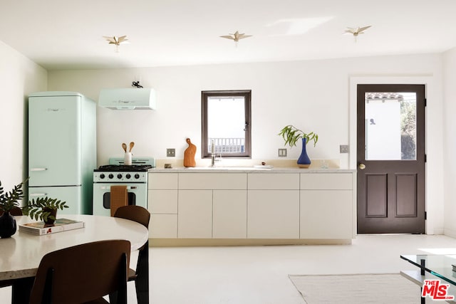 kitchen with a healthy amount of sunlight, white appliances, white cabinetry, and extractor fan