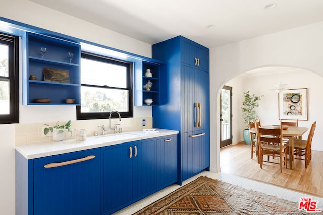 kitchen with a healthy amount of sunlight, light wood-type flooring, and blue cabinetry