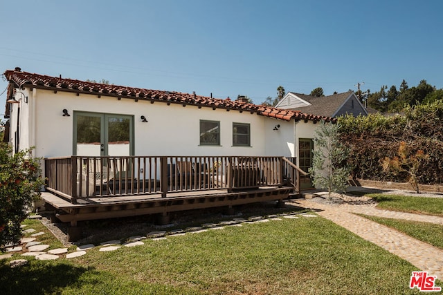 back of property with a lawn and a wooden deck