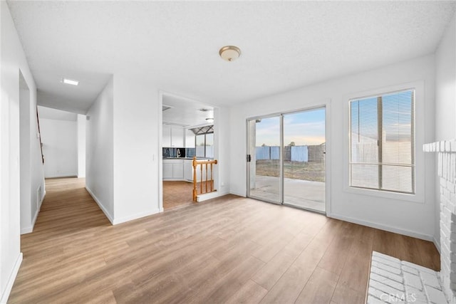 unfurnished living room with light hardwood / wood-style floors and a textured ceiling