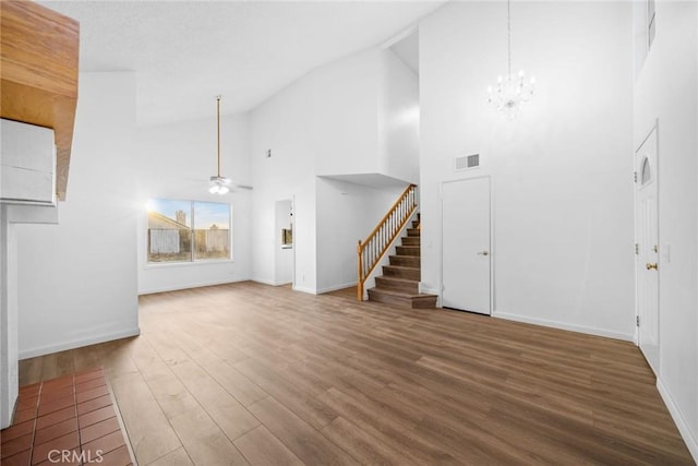 unfurnished living room featuring ceiling fan with notable chandelier, hardwood / wood-style flooring, and high vaulted ceiling