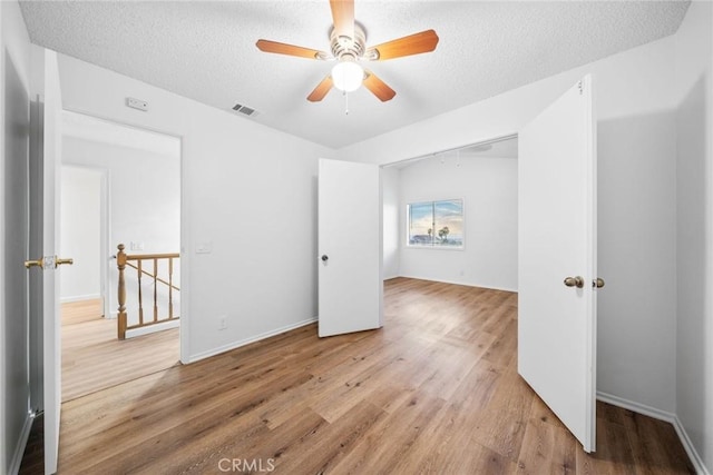 unfurnished bedroom featuring ceiling fan, a closet, wood-type flooring, and a textured ceiling