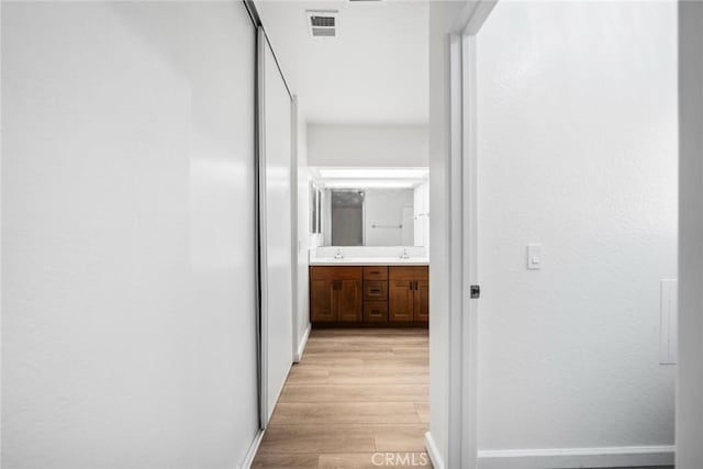 corridor featuring light wood-type flooring and sink