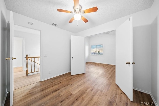 unfurnished bedroom with hardwood / wood-style floors, ceiling fan, a textured ceiling, and a closet