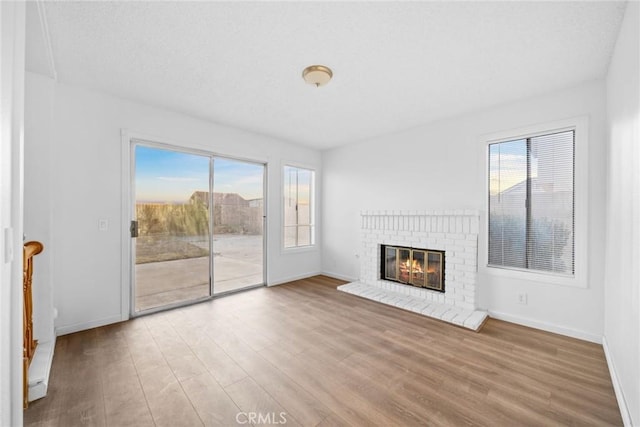 unfurnished living room featuring a healthy amount of sunlight, light wood-type flooring, and a fireplace