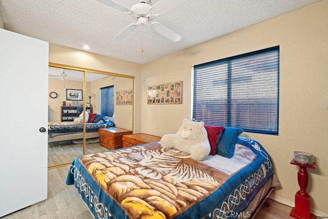 bedroom featuring a closet, a textured ceiling, a ceiling fan, and wood finished floors