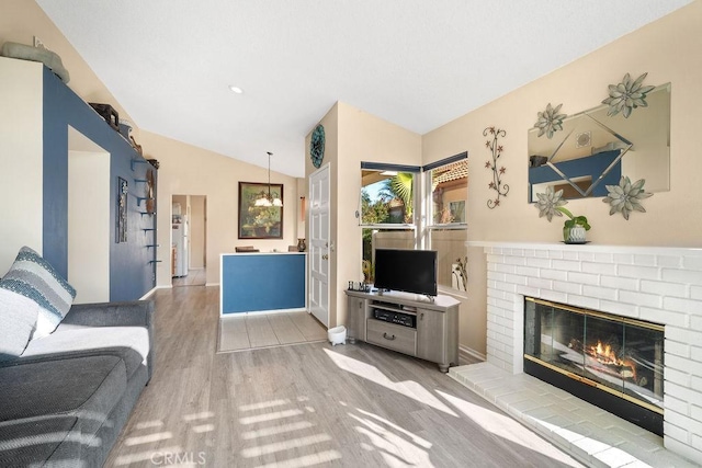 living area featuring lofted ceiling, wood finished floors, and a fireplace