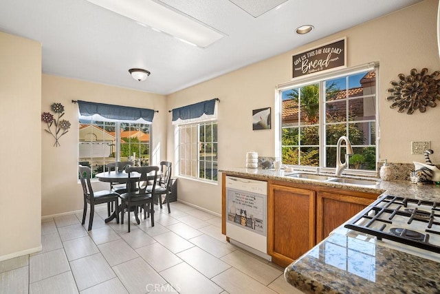 kitchen with dishwasher, plenty of natural light, brown cabinets, and a sink