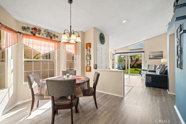 dining space with an inviting chandelier, plenty of natural light, wood finished floors, and a textured ceiling