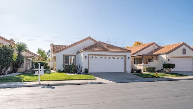 view of front of house featuring a front yard, an attached garage, stucco siding, concrete driveway, and a tiled roof